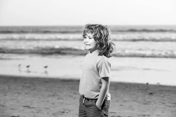 Kind jongen in t-shirt met hand in hand wandelen op het zomerstrand. — Stockfoto