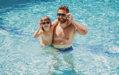 Baba oğul havuzda yüzüyor, yaz ailesi. Havuz partisi. Aile eğlencesi. Yaz tatili. Baba ve oğul havuzda..
