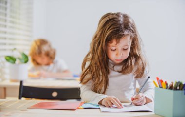 Okulda sınıftaki çocuklar. Eğitim, ilkokul, öğrenim ve insan konsepti - kalemleri ve defterleri olan bir grup okul çocuğu.