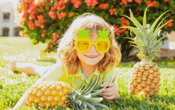 Criança usando óculos de sol engraçados com abacaxi. Miúdo com fruta tropical. Férias exóticas. Fruta para crianças. Férias de verão. — Fotografia de Stock