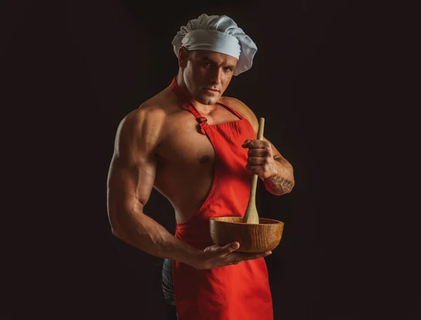 エプロンを着たセクシーな料理人。黒を基調とした筋肉料理。スポーツダイエット. — ストック写真