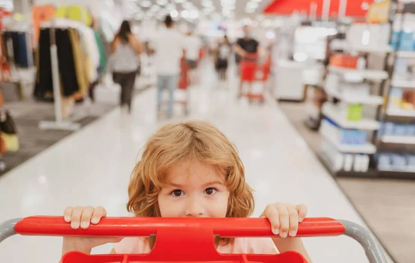 Retrato de close-up de criança no supermercado ou supermercado com mercadorias no carrinho de compras. — Fotografia de Stock