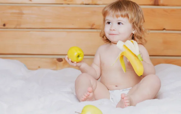 新鮮な果物を持つ子供。幸せな幼児はリンゴとバナナを食べる。子供の栄養. — ストック写真