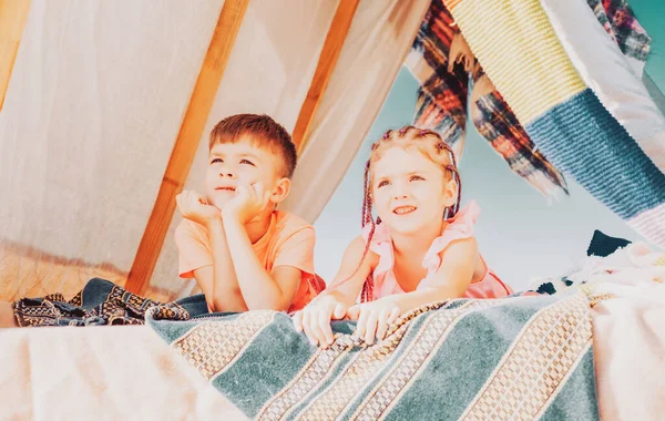 Sister brother relationships. Summer camping. Children in homemade tent. Cute kids camping. Having fun outdoors.