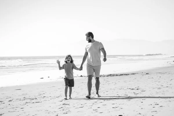 Πατέρας και γιος περπατούν στη θάλασσα. Ο μπαμπάς και το παιδί κρατιούνται χέρι-χέρι και περπατούν μαζί. — Φωτογραφία Αρχείου