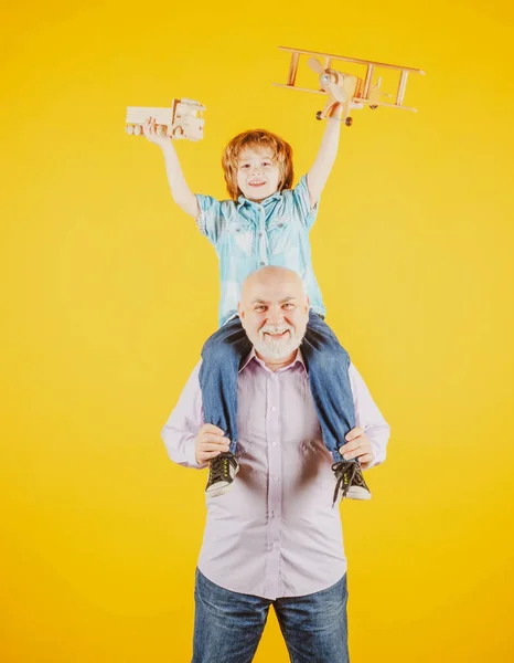 Velho avô e neto criança com avião de brinquedo e caminhão de brinquedo de madeira. Homens geração avô e neto. — Fotografia de Stock