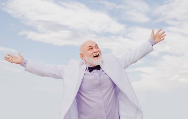 Kaygısız, eski moda kazananı yaşlı, yaşlı, olgun bir adam. Beyaz takım elbiseli başarılı erkek eğleniyor..