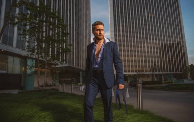 Takım elbiseli modern iş adamı arka planda şehir manzarasıyla dışarıda duruyor..