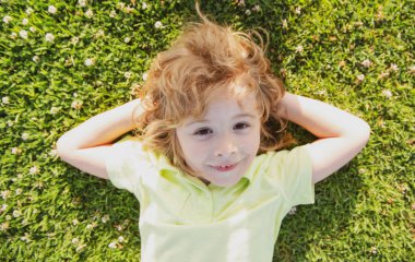 Çocuklar yazın tadını çıkarıyor. Yazın doğa parkında çim portresi üzerinde yatan çocuklar. Şaşırdım. Çocukları heyecanlandırdım..
