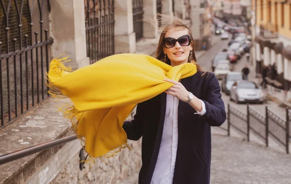 Hermosa modelo femenina con bufanda soplando en el viento en la ciudad de verano en Europa. Mujer de moda posando en el fondo de la calle. Bufanda ventosa. —  Fotos de Stock