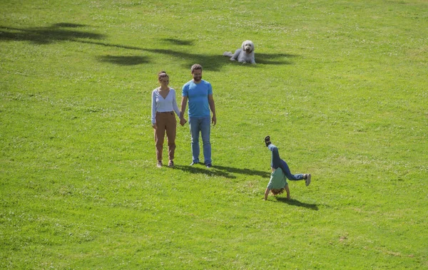 Família feliz descansando juntos na grama verde, se divertindo ao ar livre. — Fotografia de Stock