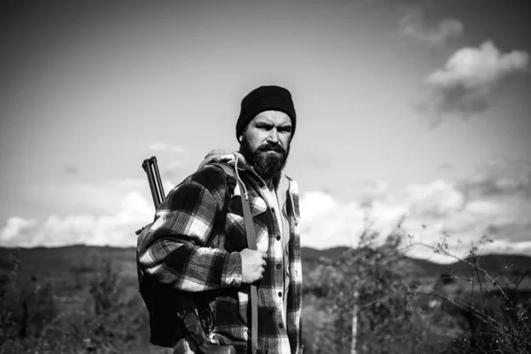 Jägare med hagelgevär pistol på jakt. Skäggiga hunter mannen hålla pistolen och promenader i skogen. Hösten. — Stockfoto