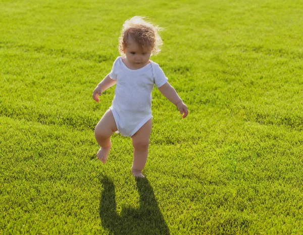 Premier pas. Bébé jambes nues debout sur l'herbe verte. — Photo