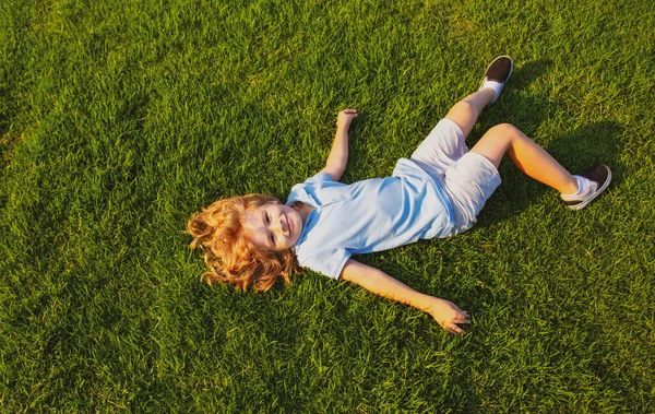 Happy smiling boy relaxing on the grass. Top view with copy space. — Stock Photo, Image