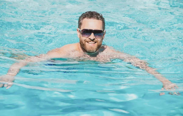 Άνθρωπος στις καλοκαιρινές διακοπές. Ο τύπος με τα γυαλιά ηλίου χαλαρώνει στην πισίνα. Θερινό θέρετρο πισίνα. — Φωτογραφία Αρχείου