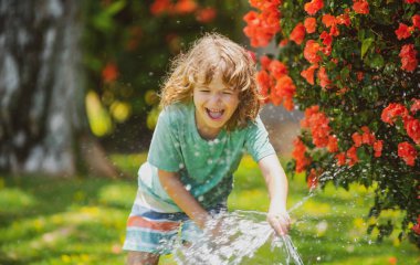 Çocuk eğleniyor. Komik çocuk doğal ortamda mutlu bir şekilde gülümsüyor. Küçük çocuk temiz havada eğleniyor. Komik olmak en büyük özelliklerimden biridir. Güneşli yaz gününde bahçedeki çiçekleri sulamak..