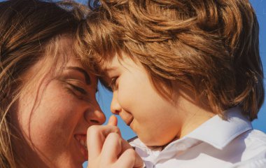 Anneler Günü. Çocuk evlat, anneye sarıl. Anne ve çocuk gülümsüyor ve sarılıyorlar. Aile tatili ve birliktelik.