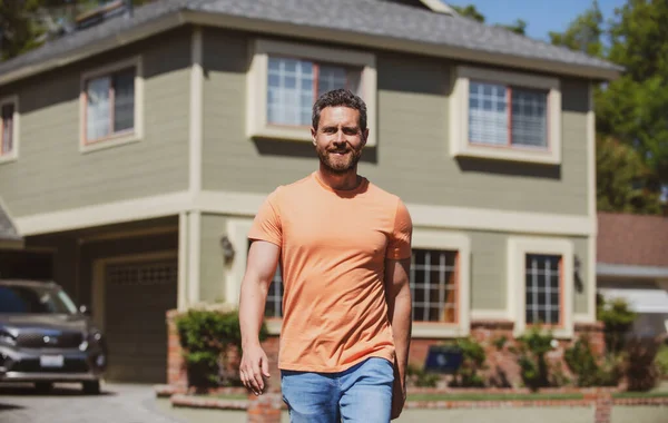 Porträt eines selbstbewussten Mannes, der vor seiner neuen Heimat steht. Erfolgreicher Immobilienmakler kauft Haus für Investitionszwecke. Glücklich und gutaussehend. — Stockfoto