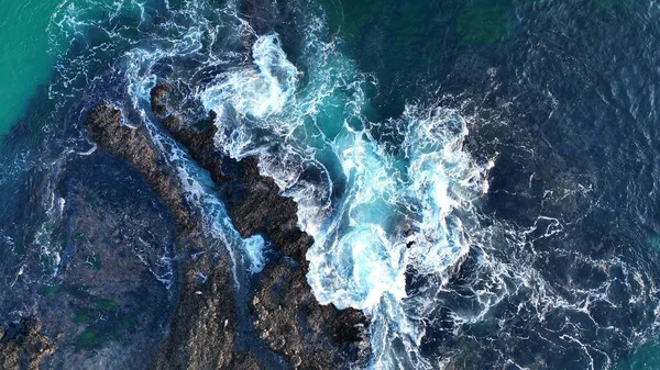 Dalgaların ve kayalıkların havadan görünüşü. Okyanus dalgaları kayaların üzerinde kırılıyor, insansız hava aracının havadan görünüşü. — Stok fotoğraf