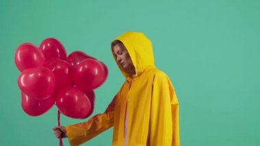 Sarı kazaklı çılgın kız elinde kırmızı balon tutuyor. Sevgililer Günü. Gri arkaplanda izole.