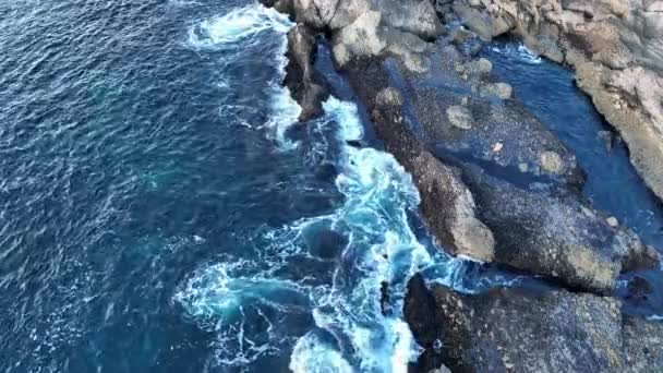 Légi felvétel hullámokról és sziklákról. Tengeri hullámok törnek át a sziklákon. Hullámok csobognak a sziklákon, a drón légi kilátása. — Stock videók