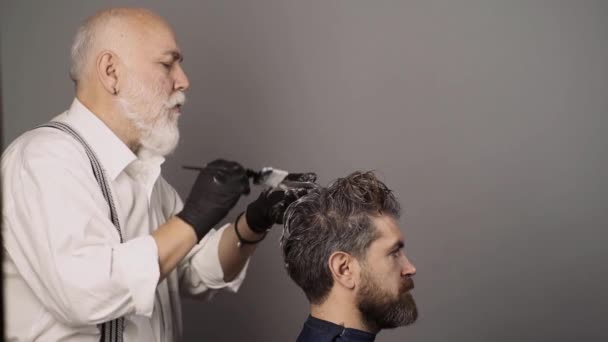 Coloring man hair process. Hair coloring man. Making of a dyed hair for a bearded hipster guy. Beard coloring man agains grey hair. Bearded man, barber shop. — Stock Video