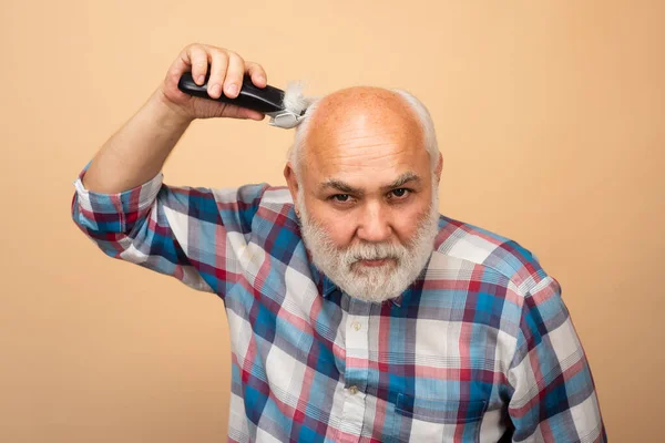 Człowiek z brodą obcinający sobie włosy nożykiem. w średnim wieku łysy człowiek strzyżenie, dojrzałe łysienie i utrata włosów koncepcja. — Zdjęcie stockowe