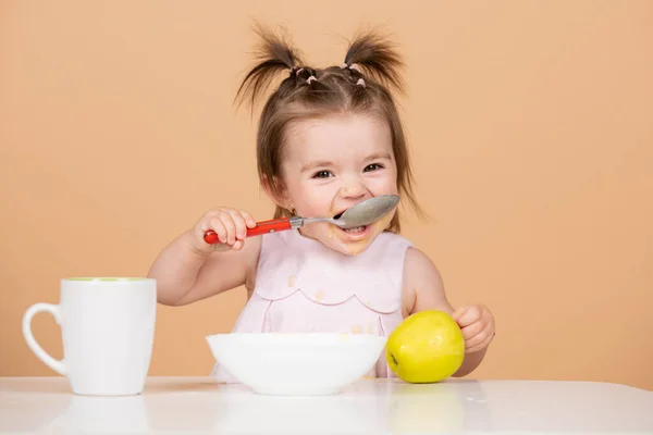 Bebé comiendo comida para niños. Primera comida de los bebés. El niño come solo con una cuchara y un plato. — Foto de Stock
