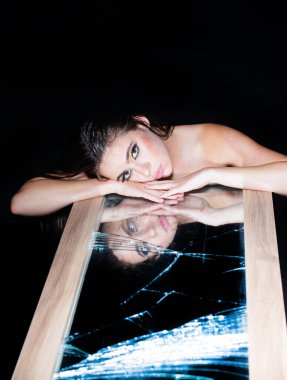 Çekici ve şehvetli görünen güzel kadın modelinin portresi. Aynalı kız. Siyaha izole edilmiş dramatik stüdyo ışığı olan güzel bir yüz..
