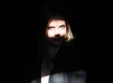 Çekici bir kadın, genç ve şehvetli bir model siyah stüdyoda baştan çıkarmaya çalışıyor. Gölgede zarif bir kadının moda portresi, göz kamaştırıcı bir ışık. Kadınların yüzüne gölge ve ışık yansıtan yaratıcı portreler, gözler