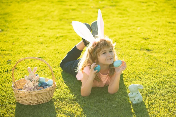 Vrolijk Pasen. Paashaas kinderen. Kind jongen in konijn Pasen oren schilderen eieren. — Stockfoto