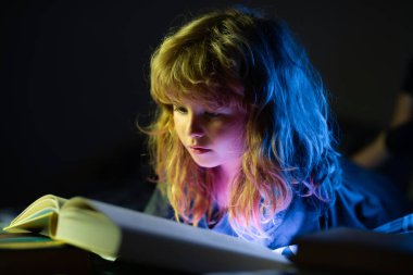 Mutlu çocukluk, rüya gören çocuk. Yatakta uzanmış kitap okuyan sevimli bir çocuk. Çocuk yatmadan önce kitap okuyor..