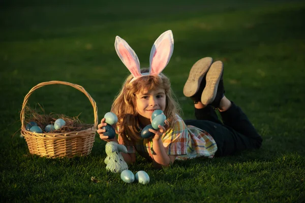 Tavşan kulaklı çocuk tavşancık. Bahçede Paskalya yumurtası avı. Çocuk tarlada oynuyor, paskalya yumurtası avlıyor.. — Stok fotoğraf