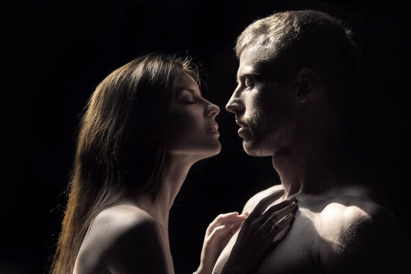 Portrait of lovely couple in love. Young sensual girlfriend glad to passionate kiss from her boyfriend. Handsome man embraces his woman and kisses.