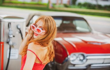 Kırmızı retro otomobil. Eski Amerikan arabası. Benzin istasyonunda gülümseyen kadın.