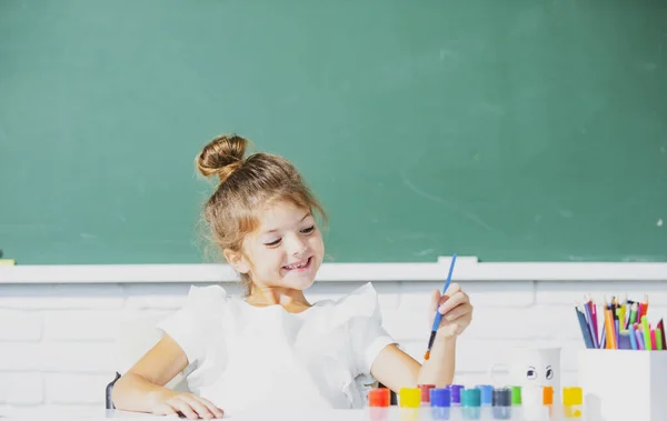 Divertida alumna de escuela dibujando un cuadro. Lindo niño preescolar pequeño dibujo en la escuela. — Foto de Stock