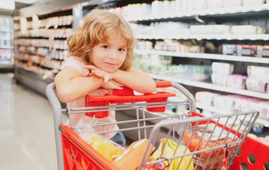 Markette ya da süpermarkette alışveriş arabası olan tatlı bir çocuk..