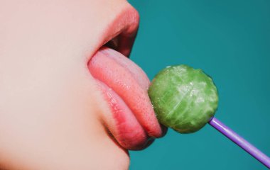 Dudaklarını yalıyor. Lolipop yalayan bir kadın, sanat afişi, lolipoplu kırmızı dudaklar. Lolli pop ile seksi kırmızı kadın ağzı ve dili. Tasarım için resim baskısı.