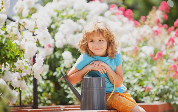 Little farmer with watering can in garden planting flowers. — Stock Photo, Image