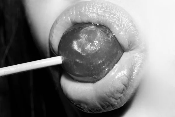 Lollipop in woman mouth, red lipstick. Woman licking a red shiny lollipop. Close up. Sexy woman with lollipop in sensual mouth. — Stock Photo, Image