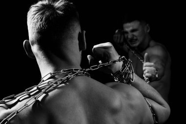 Saldırgan adam zincirlerini kırmış. Kas gücü. Güçlü ve seksi erkek modeller..