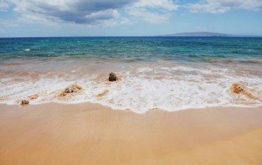 Kumlu sahilde mavi okyanus dalgası. Yaz mevsiminde gün batımında plaj. Plaj manzarası. Tropik deniz manzarası, sakinlik, dinlendirici güneş ışığı.