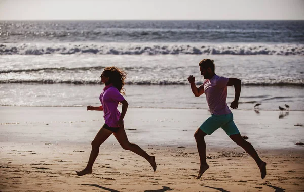 Пара біжить на пляжі. Спорт і здоровий спосіб життя, силует друзі бігають на заході сонця на пляжі . — стокове фото