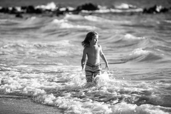 Niño en la costa. Un niño jugando en el océano. Vacaciones en el mar. El niño en olas. — Foto de Stock