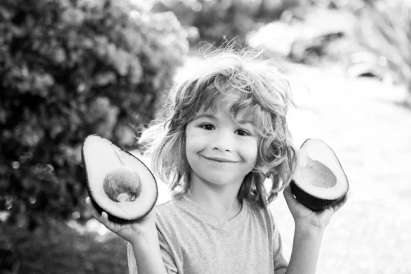 Glad pojke på gården har kul med avokado. Barn sommar vitamin. — Stockfoto