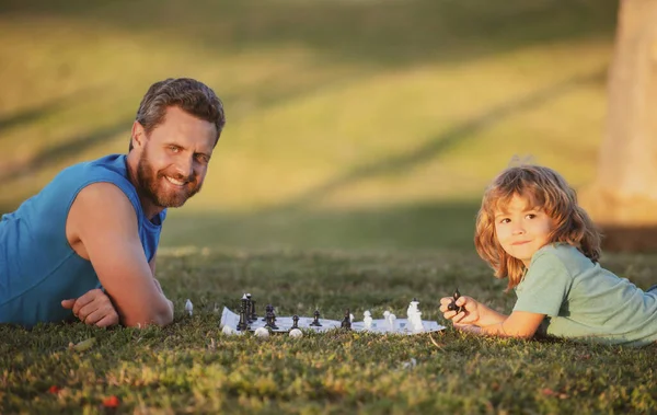 Pai e filho jogando xadrez passar tempo juntos ao ar livre. Inteligente criança concentrada e pensante enquanto joga xadrez. — Fotografia de Stock