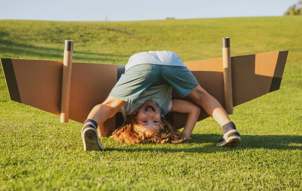 Lustigt barn upp och ner på gräs. Barndomsfantasi, barndröm till äventyrsresor. Resor och semester med barn. Barn frihet och bekymmersfri koncept — Stockfoto