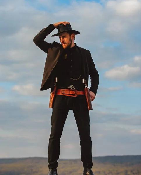 Seriff vagy cowboy fekete öltönyben és cowboy kalapban. Egy férfi nyugati pisztollyal és rendőrbírói lőszerrel. Amerikai nyugati, seriff.. — Stock Fotó