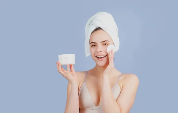 Beautiful smiling girl with clean fresh skin. Facial treatment. Cosmetology beauty and spa. Girl apply skincare cream on face, woman wrap towel on head put facial creme on doing morning healthy skin. — Stock Photo, Image