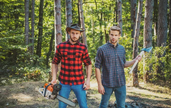 Man woodcutter holding ax. Axe in lumberjack hands cutting wood. Lumberman with a chainsaw in forest. Concept of a logging woodcut